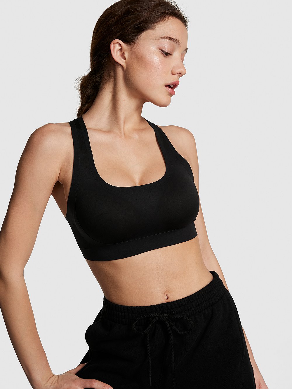 Victoria's Secret, PINK Unwind Stretch Racerback Sports Bra, Pure Black, onModelFront, 1 of 3 Ruby is 5'6" and wears 32A or Small